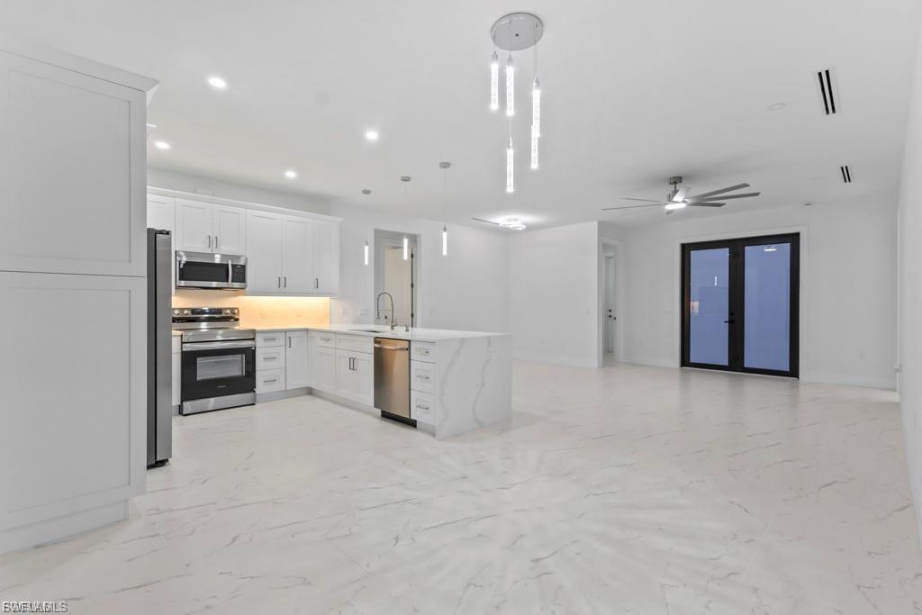 Open-concept living space featuring a modern kitchen with white cabinetry, stainless steel appliances, and a waterfall island