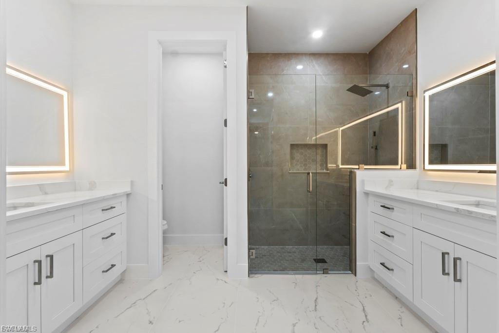 Spacious bathroom with a walk-in shower featuring a rain showerhead and recessed niche