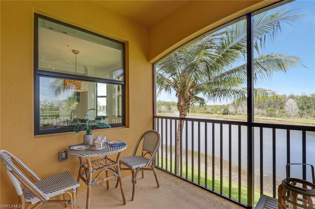 Expansive screened balcony featuring a water backdrop, lush palm trees, and a durable concrete floor