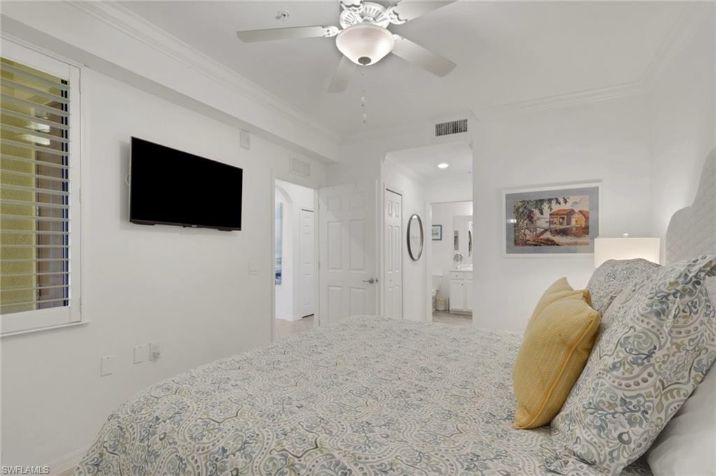 Bedroom with crown molding, a ceiling fan with integrated lighting, and a wall-mounted entertainment display