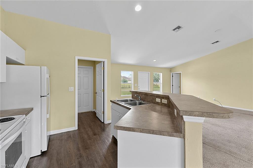 Kitchen featuring white appliances, a double basin sink, and a breakfast bar