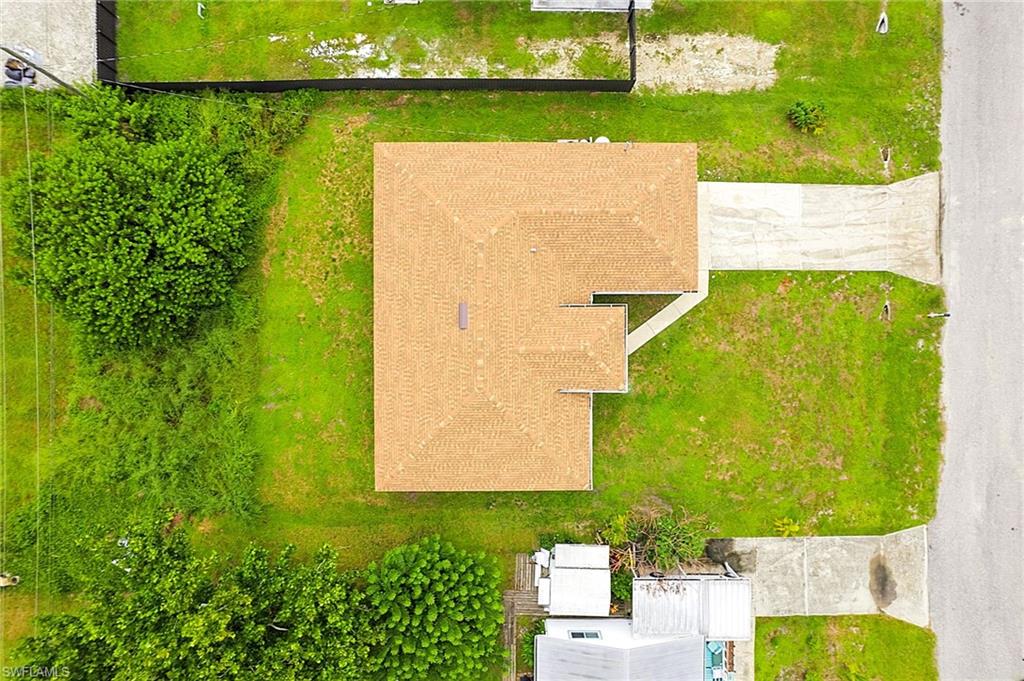 Single-story property featuring a gabled roof with shingles, a concrete driveway, and surrounding green space