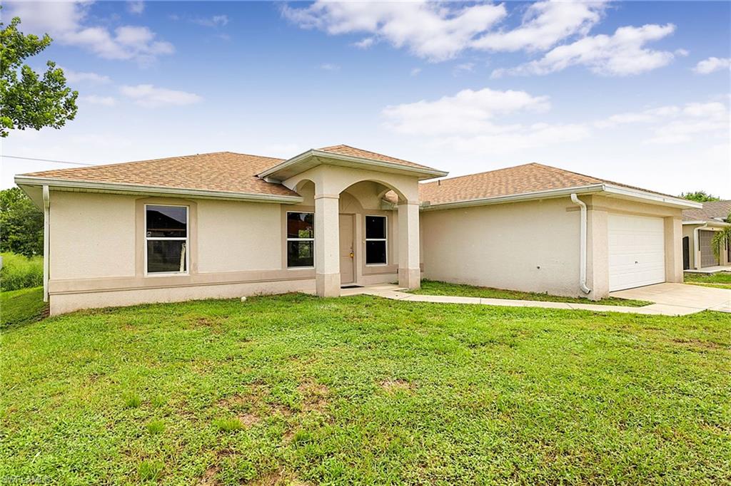 Contemporary stucco exterior featuring a covered entry, multiple windows, a two-car garage, and a concrete driveway