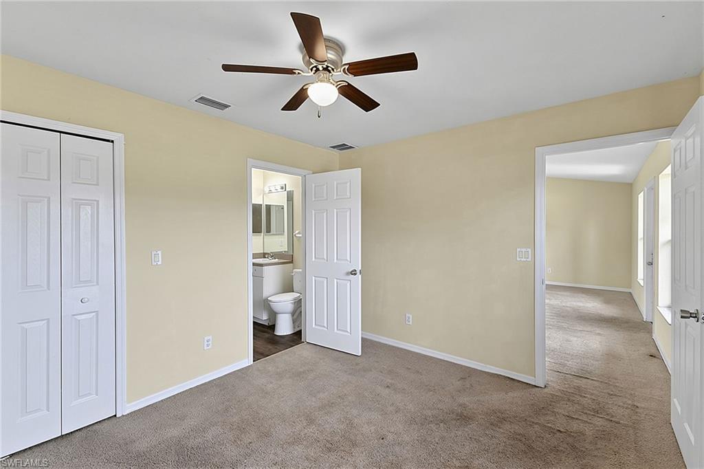 Carpeted room with light-toned walls, featuring a ceiling fan with integrated lighting