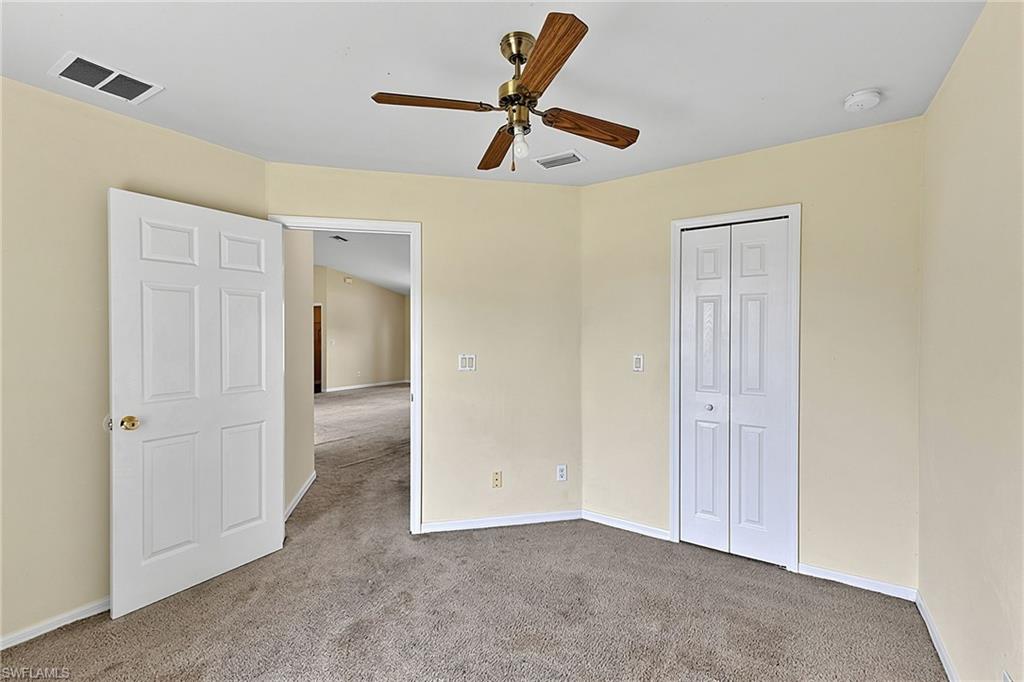 Carpeted room featuring a ceiling fan, light beige walls, a white bi-fold closet door, and a white six-panel door