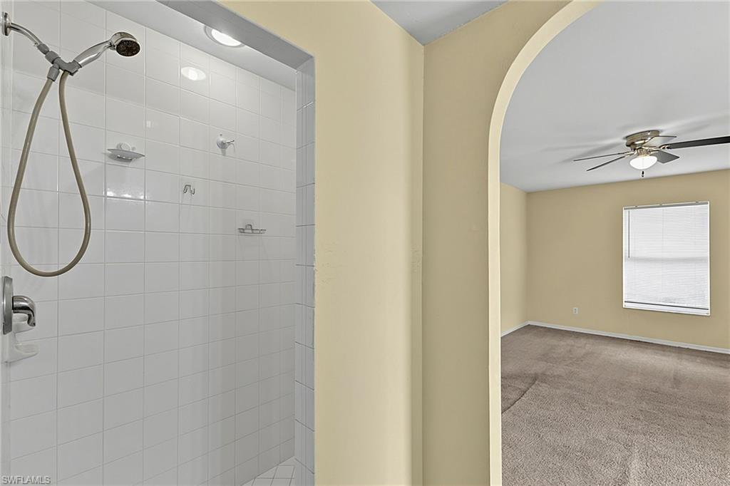 White tiled shower stall with recessed lighting and chrome fixtures