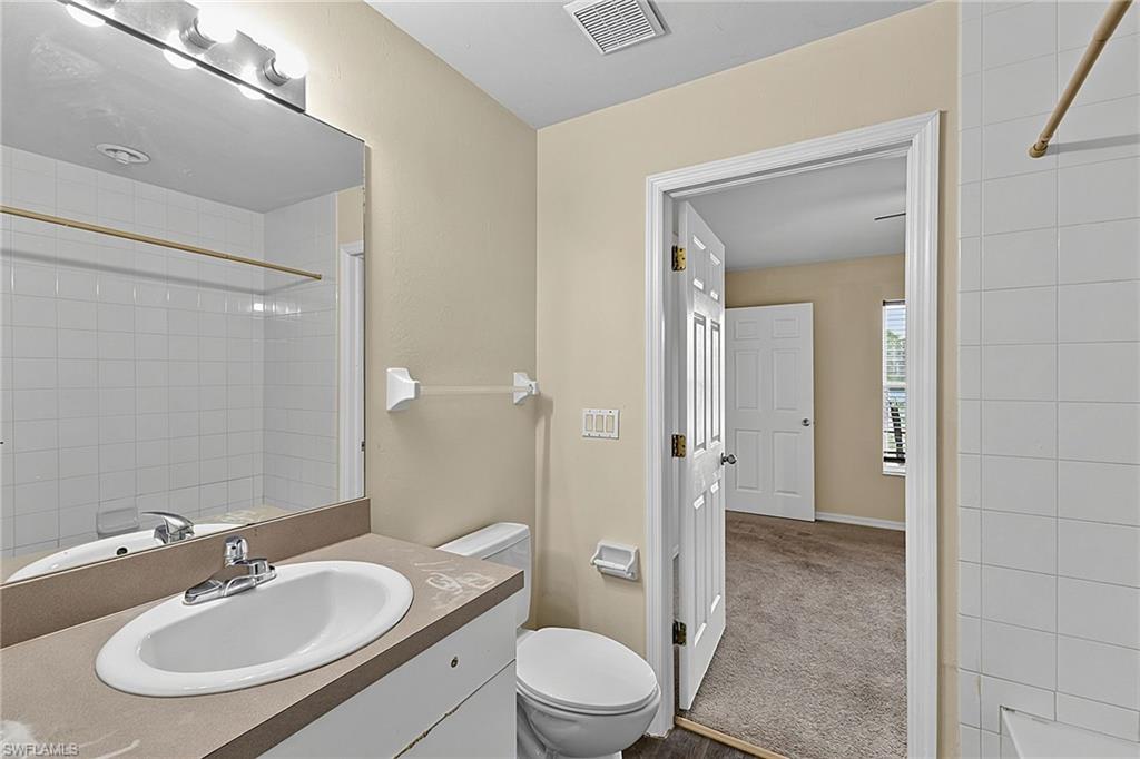 Bathroom featuring a single vanity with an integrated sink, a large mirror, and overhead strip lighting