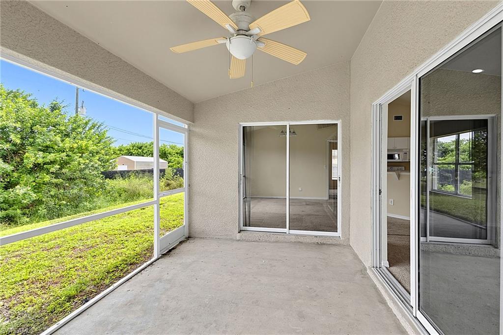 Screened concrete patio featuring a vaulted ceiling with a mounted ceiling fan, stucco walls, and dual sliding glass doors