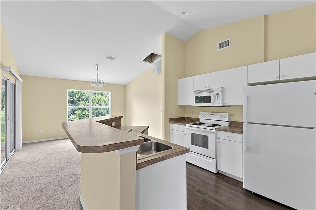 Open-concept kitchen featuring white cabinetry, a double basin stainless steel sink, and white appliances