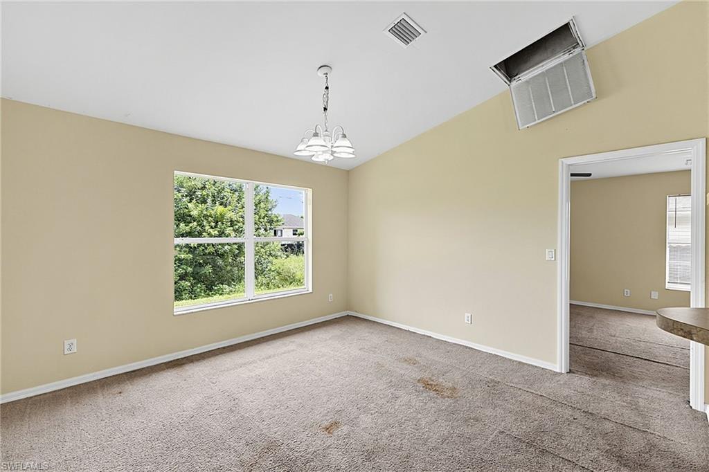 Spacious interior with vaulted ceilings, a large window providing abundant natural light, and a decorative chandelier