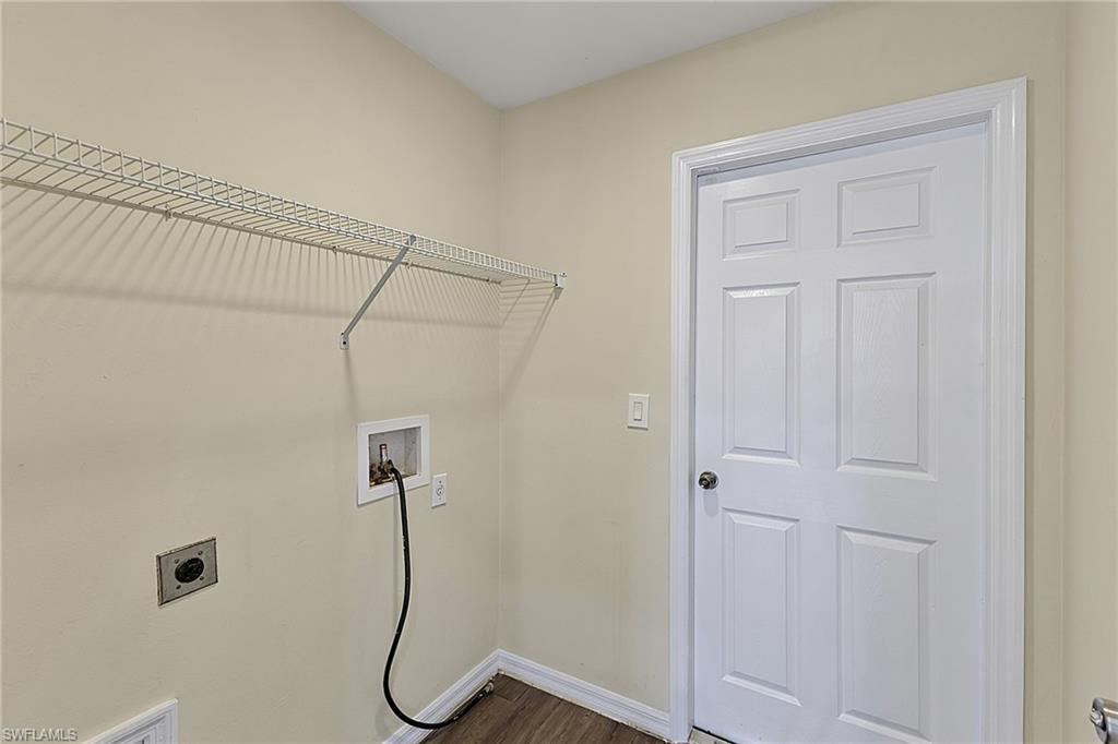 Utility room featuring a wire shelving unit, wood-finish flooring, and a six-panel door