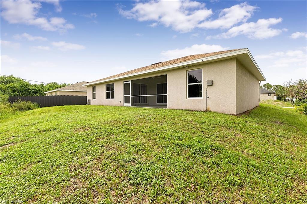 Expansive backyard featuring a sloped lawn and a perimeter fence