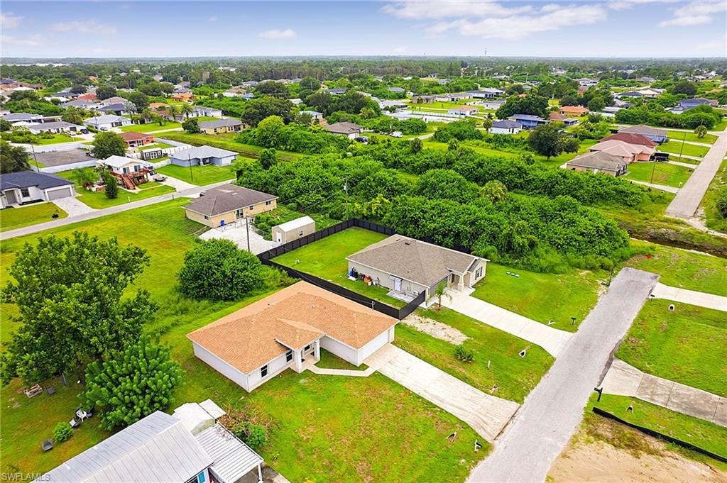 Aerial perspective showcasing a residential neighborhood with single-story homes, expansive green lawns, and mature trees