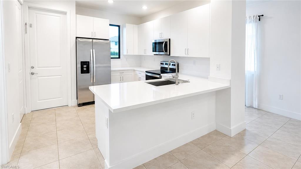 Modern kitchen featuring white cabinetry and light-toned tile flooring