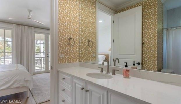 Ensuite bathroom featuring vanity, wallpapered walls, ornamental molding, and a shower with curtain