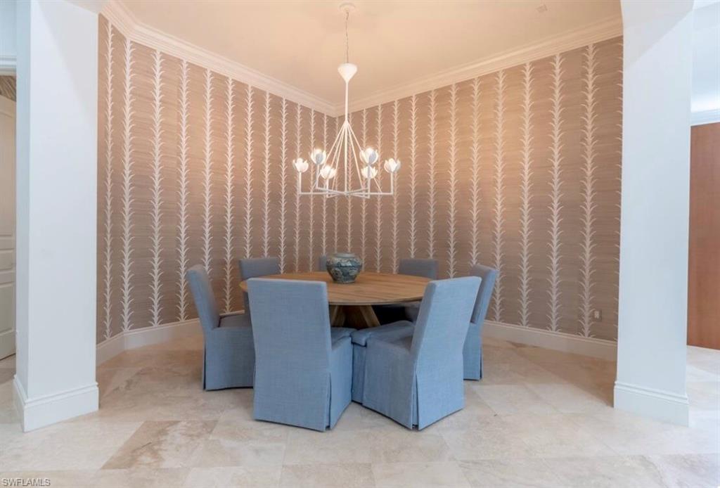 Dining room with crown molding, wallpapered walls, and a chandelier