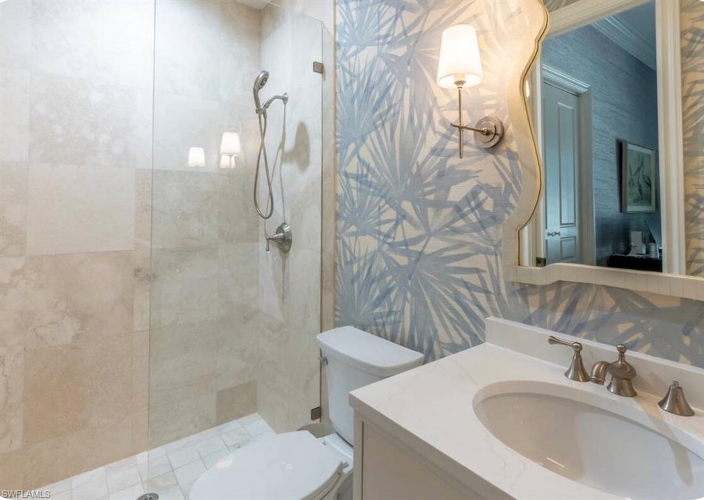 Full bath featuring wallpapered walls, vanity, and a walk in shower
