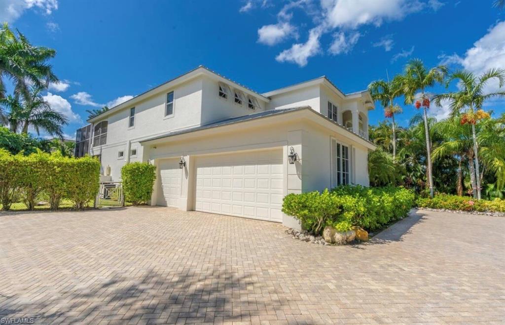 View of side of home with stucco siding, decorative driveway, and an attached garage