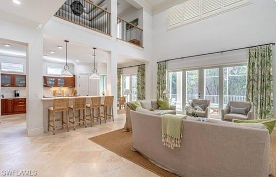 Living area with ornamental molding, a high ceiling, recessed lighting, and french doors