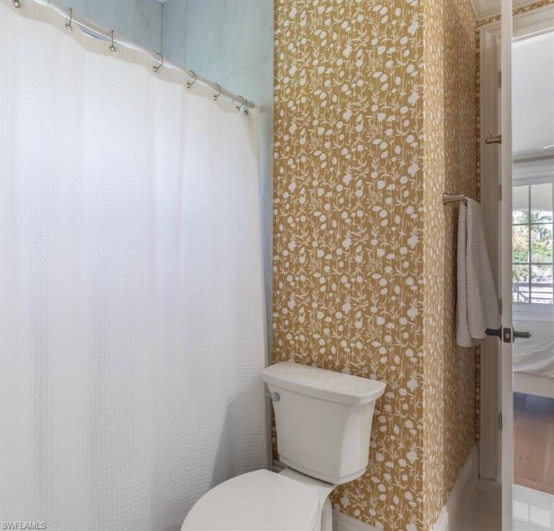 Full bath featuring curtained shower and wallpapered walls