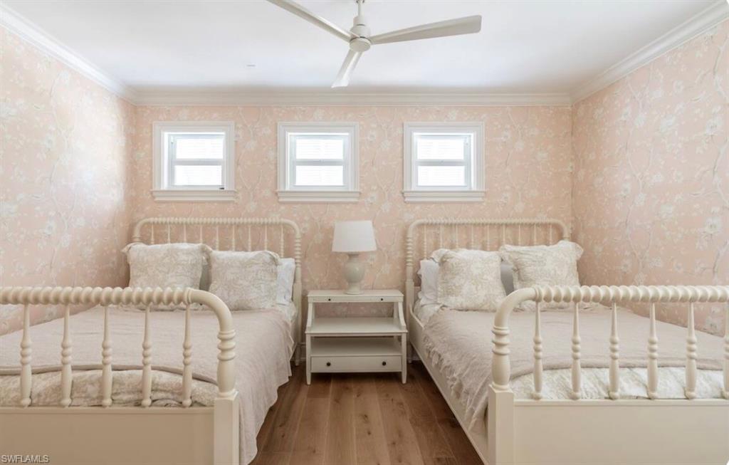Bedroom with ornamental molding, multiple windows, wallpapered walls, a ceiling fan, and hardwood / wood-style floors
