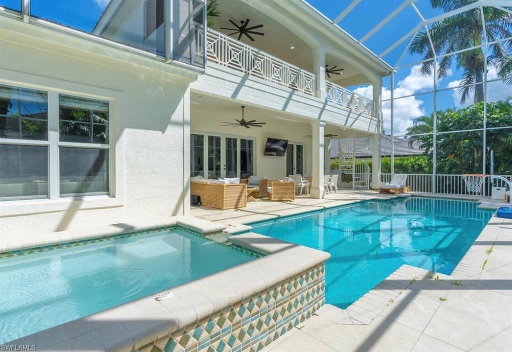 Combined pool / hot tub with outdoor seating, a patio, glass enclosure, and a balcony