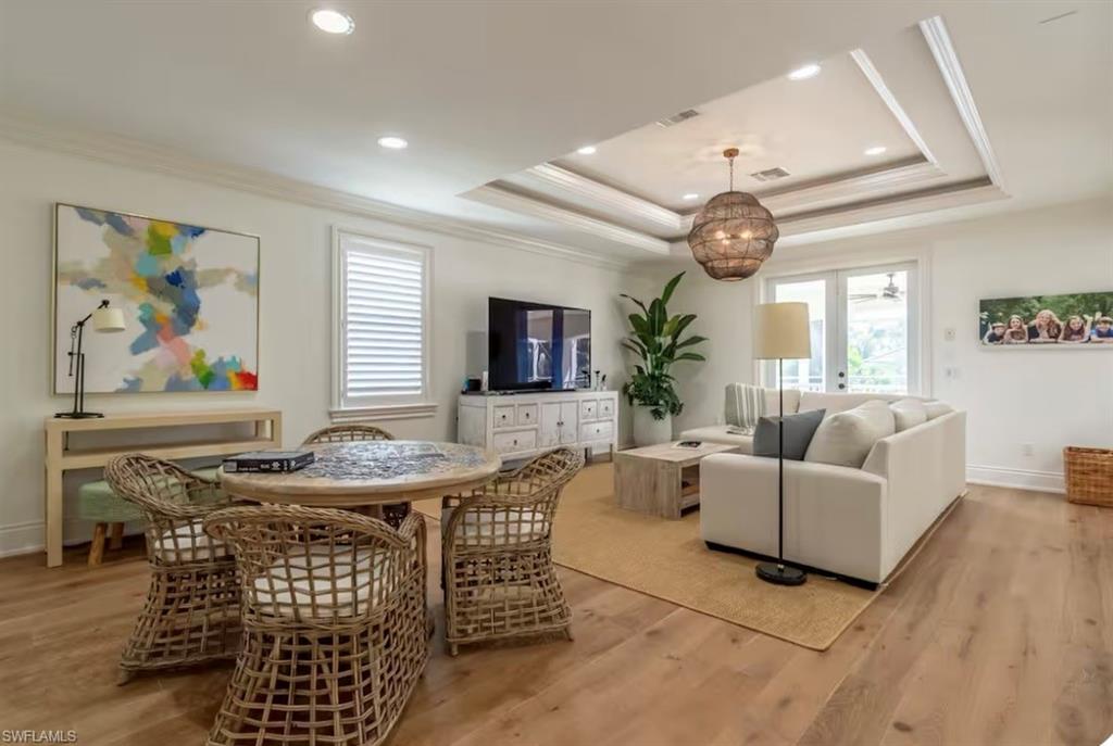 Living room with light wood-style flooring, crown molding, recessed lighting, and a tray ceiling