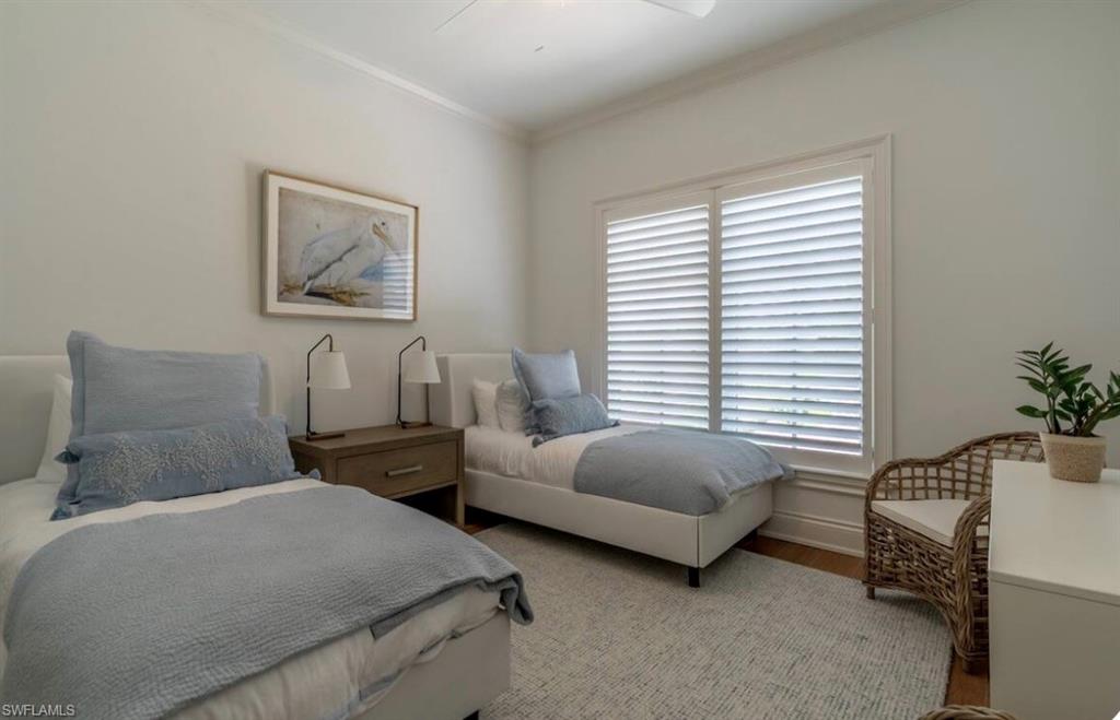Bedroom with crown molding, wood finished floors, and ceiling fan