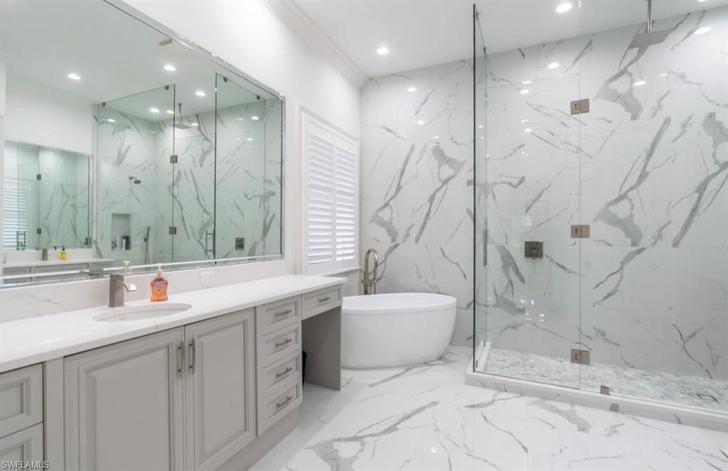Full bath featuring stone wall, vanity, recessed lighting, a marble finish shower, and a soaking tub