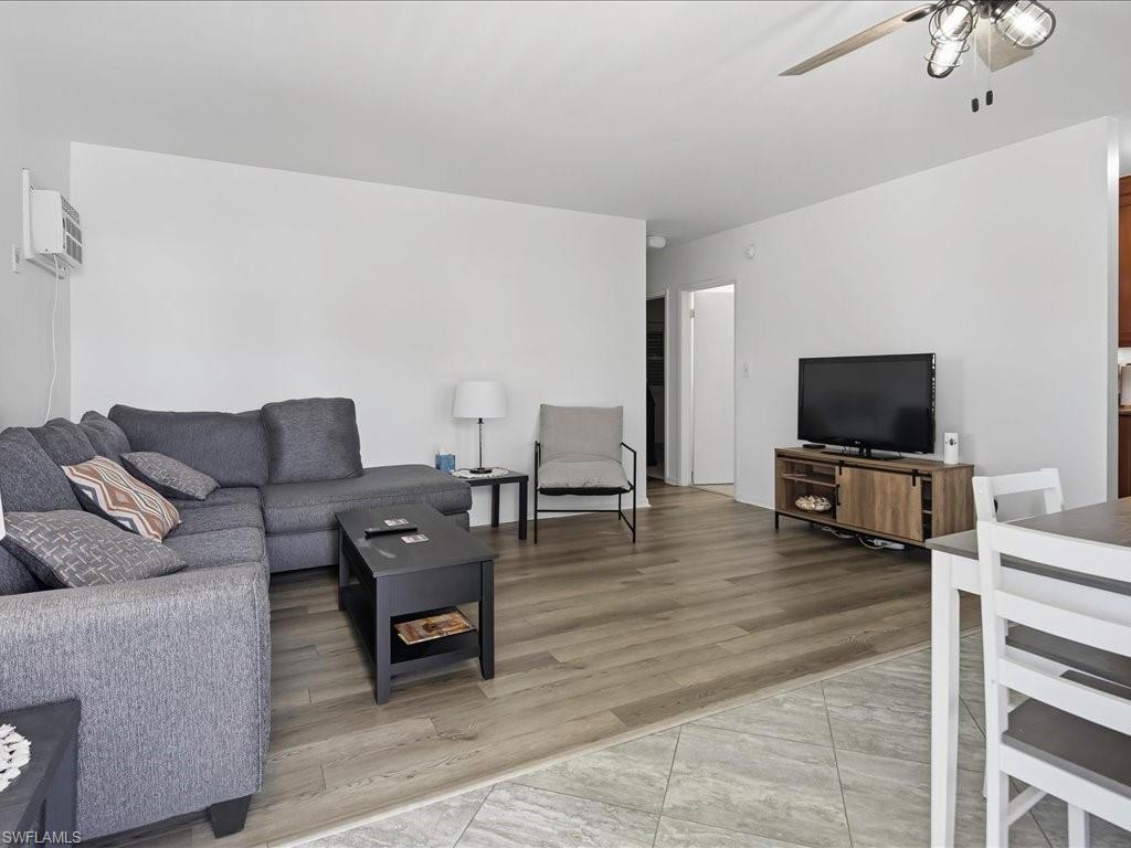 Open-concept living space with wood-finish flooring, white walls, and a ceiling fan