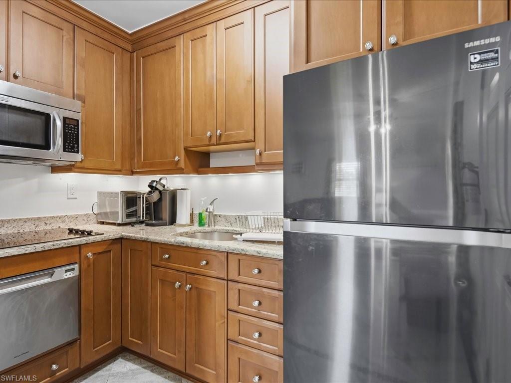 Kitchen featuring stainless steel appliances, wood cabinetry with crown molding, granite countertops, an undermount sink, and recessed lighting