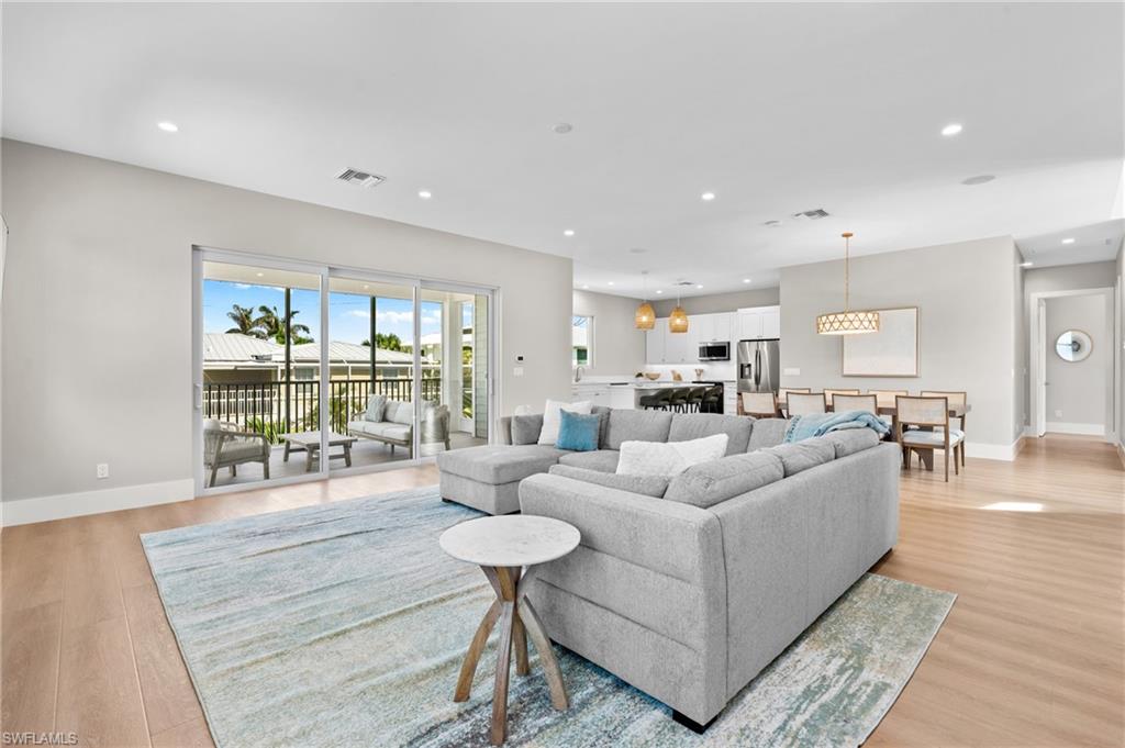 Spacious Living room with light wood finished floors, baseboards, and recessed lighting. virtually edited photo