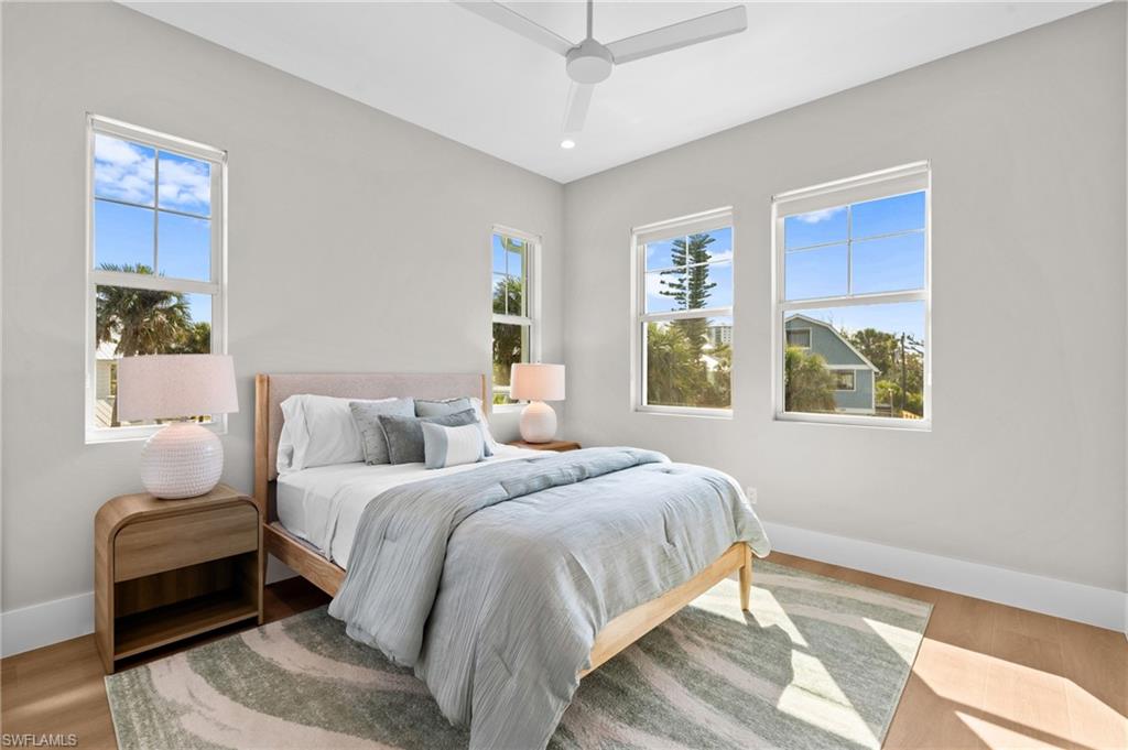 Bedroom with baseboards, a ceiling fan, and wood finished floors. virtually edited photo