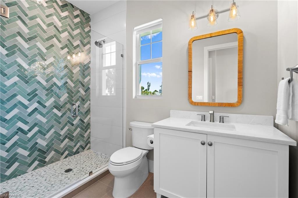 Full bath with vanity, toilet, and a tile shower. virtually edited photo