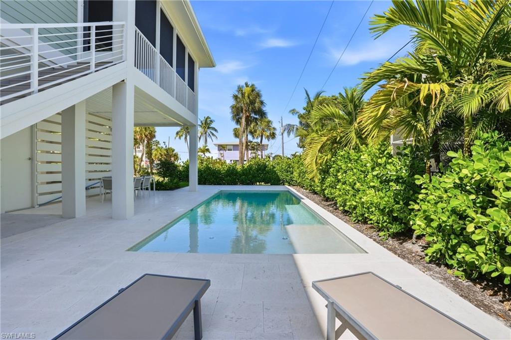 In-ground swimming pool with light-colored coping, surrounded by a light-colored paver patio