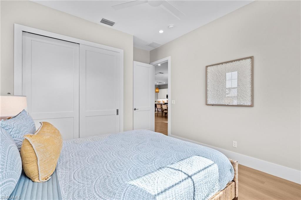 Bedroom featuring wood finished floors, a closet, ceiling fan, baseboards, and visible vents. virtually edited photo