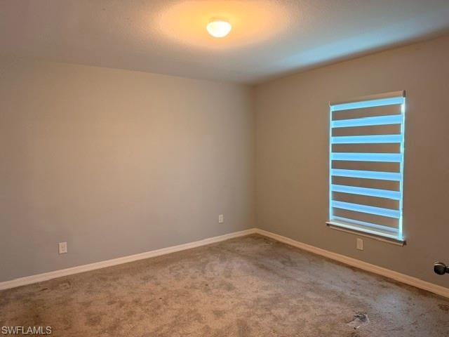 Carpeted interior room featuring light-toned wall paint and a window with horizontal blinds