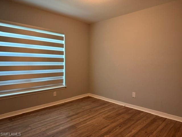 Room featuring wood-finish flooring, neutral wall paint, and white baseboards