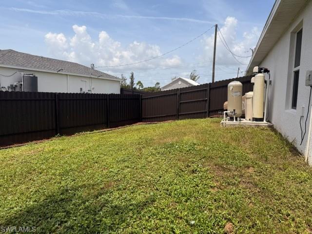 Spacious side yard featuring a dark corrugated privacy fence