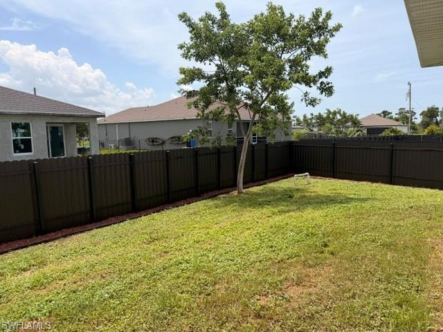 Expansive backyard featuring a mature tree, composite privacy fencing, and a perimeter of red-hued mulch
