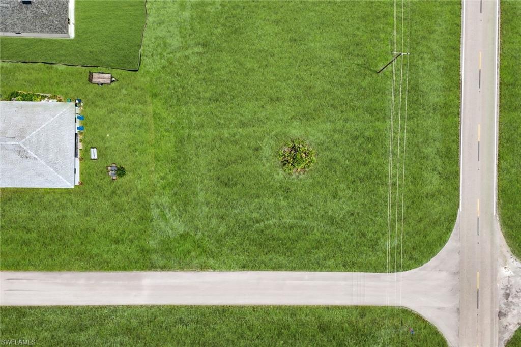 Expansive corner lot featuring a paved road and lush green space
