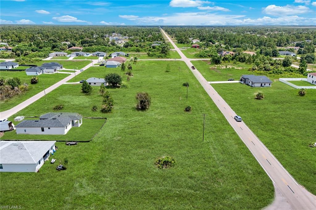 Expansive green spaces with paved roads and scattered residential structures
