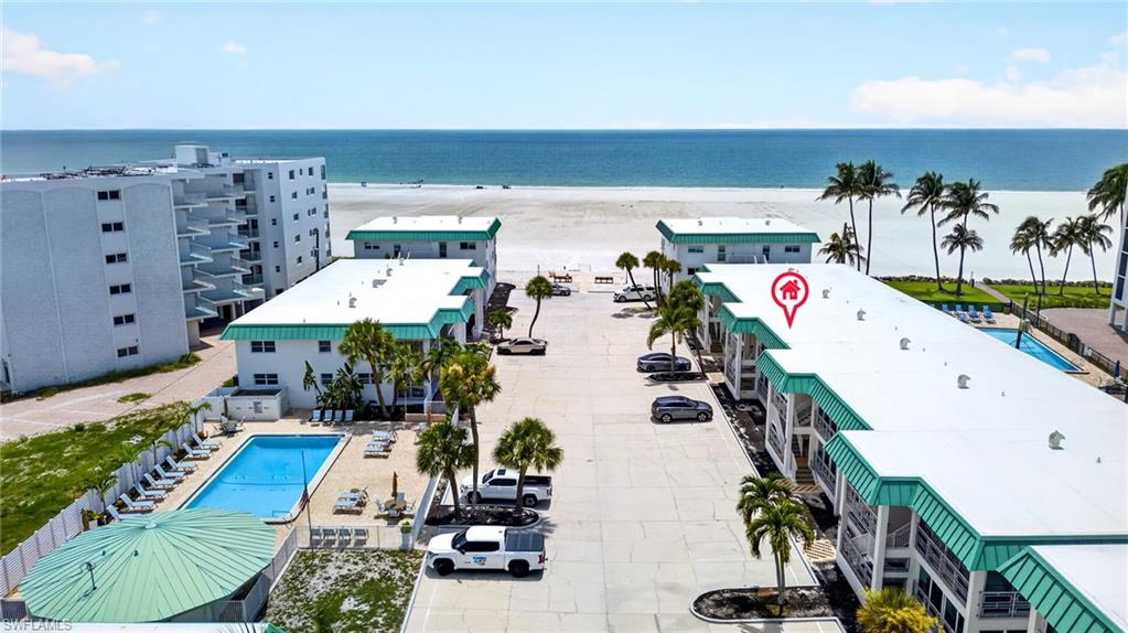 Beachfront property featuring multiple buildings, an outdoor swimming pool, and dedicated parking