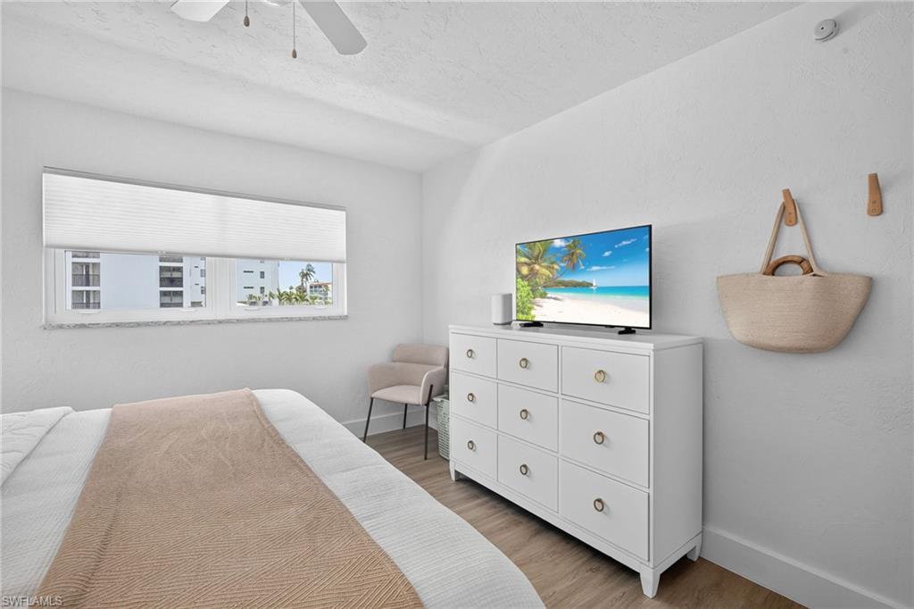 Bedroom featuring a ceiling fan, window with cellular shades, and wood-finish flooring