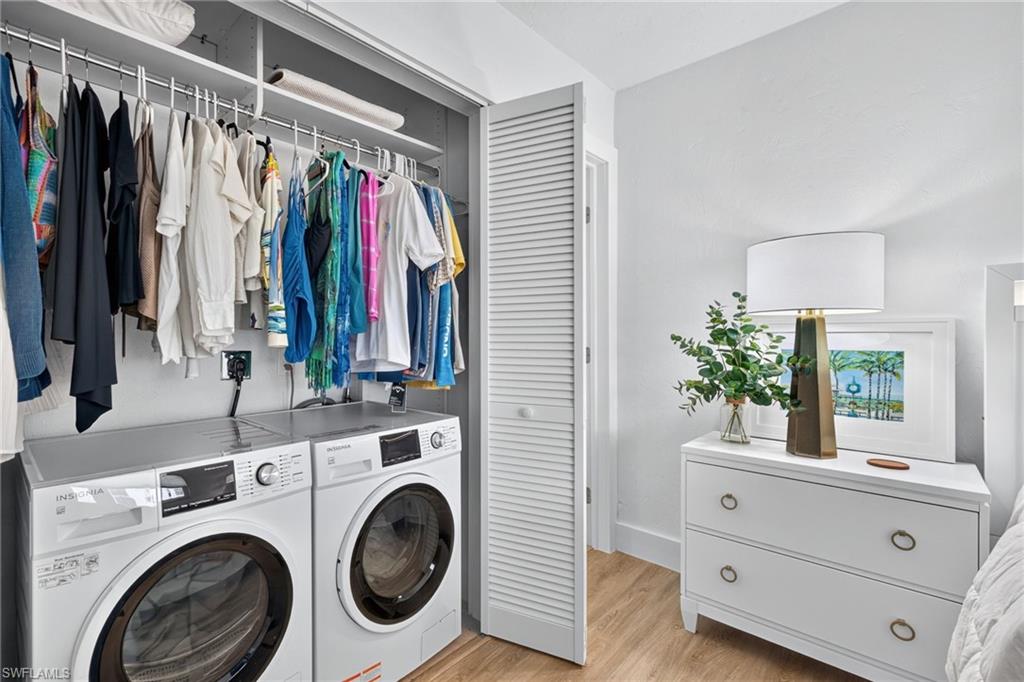 Integrated laundry closet featuring a stacked washer and dryer, upper shelving, and a hanging clothes rod