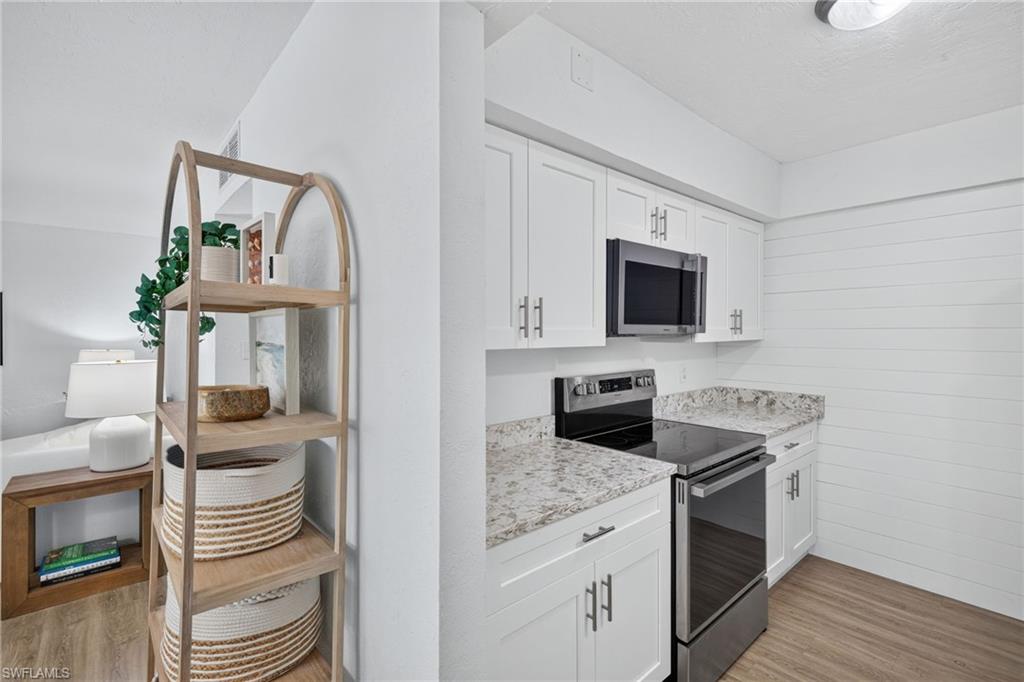 Modern kitchen featuring white shaker cabinetry, stainless steel appliances including an over-the-range microwave and electric range, and light-toned countertops