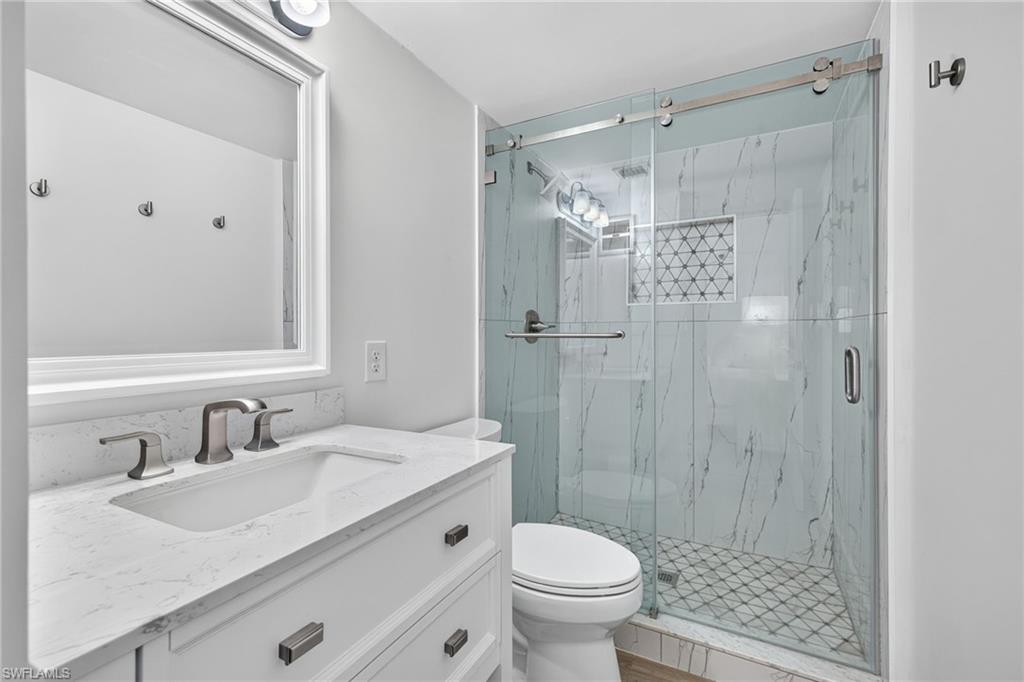 Bathroom featuring a white vanity with a stone countertop, an undermount sink, and brushed nickel fixtures