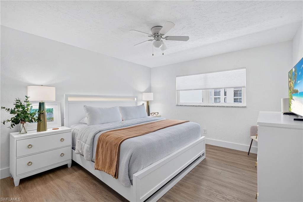 Bright room featuring wood-finish flooring, a white ceiling fan, and a window with blinds