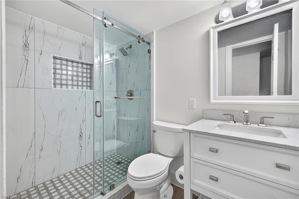 Contemporary bathroom featuring a glass-enclosed shower with marble-look tile walls and a mosaic tile floor