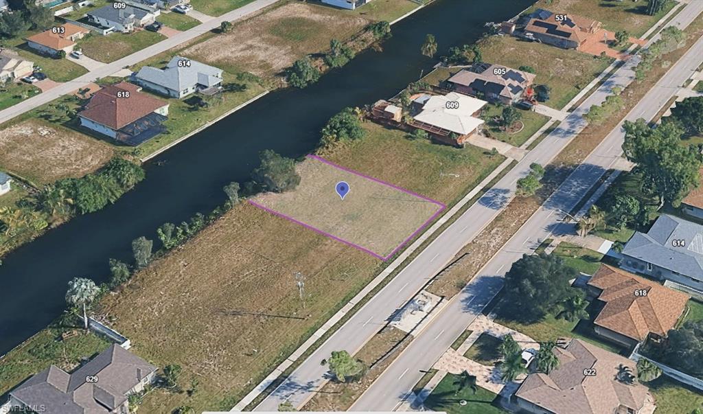 Vacant lot featuring direct canal access, a paved road frontage, and established residential surroundings